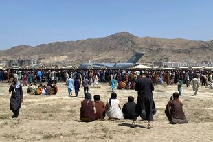 Cientos de personas esperan junto a un avión de transporte C-17 de la Fuerza Aérea de Estados Unidos en el perímetro del aeropuerto internacional de Kabul, Afganistán, el 16 de agosto de 2021. (AP Foto/Shekib Rahmani)