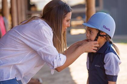 Cinthia prepara a sus hijas antes de montar. En la foto junto a Charis, una de las mellizas. Cada una tiene un casco personalizado con su nombre