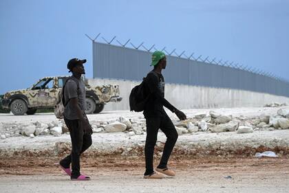 Ciudadanos haitianos caminando junto al muro fronterizo que se está construyendo en la frontera entre República Dominicana y Haití, en Pedernales, República Dominicana.