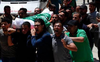 Ciudadanos palestinos corean consignas islámicas mientras llevan el cuerpo de Awad Abu Selmiya, durante un funeral de 13 militantes de Hamas en la Ciudad de Gaza
