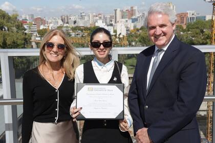 Clara Espósito recibe su diploma de graduada. La acompañan su mamá Esperanza y el rector de Di Tella, Juan José Cruces