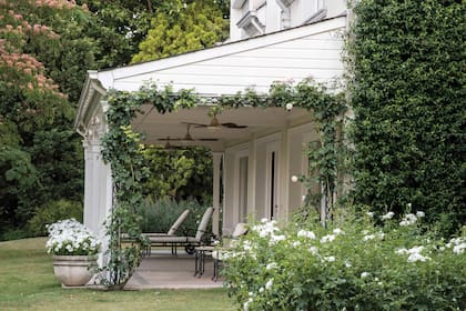 Clásica y delicada, una galería engamada en blanco invita a la contemplación del jardín.