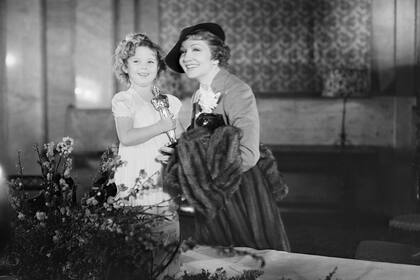 Claudette Colbert iba camino a la estación de trenes cuando regresó a recibir su Oscar; en la foto, la actriz junto a la estrella infantil Shirley Temple