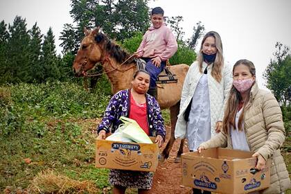 Claudia (barbijo negro) y Débora junto a un alumno y su mamá que se acercaron a la escuela a buscar los alimentos y los contenidos