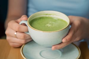 Close-up, a cup with green matcha drink in female hands.