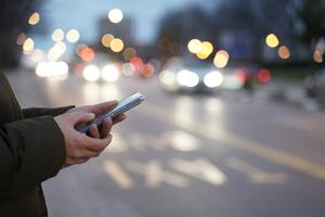 Close-up image of a woman's hands using smartphone at night on the city street, search or social networking concept, woman asking for transport via mobile application