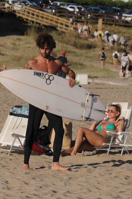 Cochito se prepara para surfear mientras Andrea toma sol en la reposera.