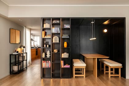 Cocina a un paso e ingenioso rincón para el comedor en un proyecto de Alejandra Nusenovich, que también se encargó del nicho, la biblioteca y la consola de paraíso de poro abierto teñido de negro, espejo con marco metálico negro.