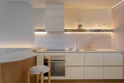 Bajomesada con frentes laqueados. Los interiores y el módulo de la heladera fueron recubiertos con melamina 'Camelia' de Faplac. Estantes de acero inoxidable de Inox ATELIER. Anafe a inducción de Teka, horno eléctrico Drean. Los frascos son de Nalda Deco, y el libro Kinfolk, de Vanity books. El set de jarra y tetera cerámica sobre la mesada es de Bárbara Bertone.