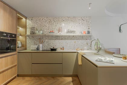 Los muebles de cocina fueron diseñados por el estudio Sara Plazibat y realizados por Moi muebles en melamina 'Paraíso' y 'Gris Tapir' (Faplac). Heladera panelable y coffee station (Smeg). En el ajuste de cocina contra la puerta, se realizó un escobero para aprovechar el espacio de guardado. Mesada de Purastone 'Tajmahal' (De Stefano) y alzada de mármol Arabescato Blanco (De Stefano).