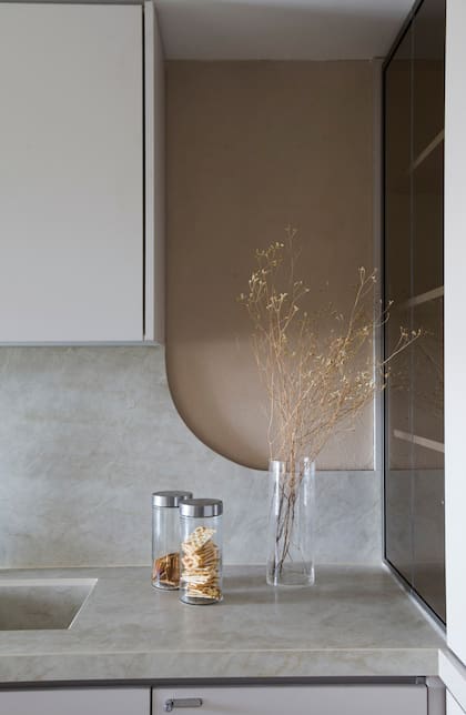 Mesada con pileta incorporada en Puraprima 'Taj Mahal' (De Stefano), ejecutada por marmolería GyG. La alzada de mesada con curva tiene revestimiento símil piedra París. Un cristalero junto a la mesada se esconde con vidrios color fumé (Shawer).