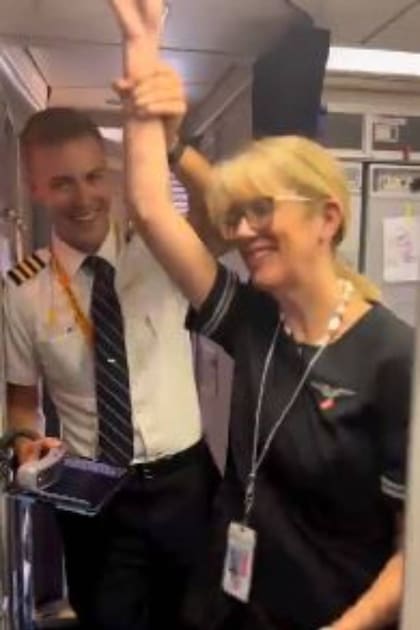 Cole Boss, piloto de United Airlines, levanta el brazo de su mamá azafata en señal de victoria y para que los pasajeros la saluden con aplausos