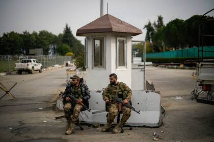 Combatientes sirios custodian la entrada al aeropuerto civil de Lakatia, en la localidad de Hmeimim, en Siria, el 16 de diciembre de 2024.(AP Foto/Leo Correa)