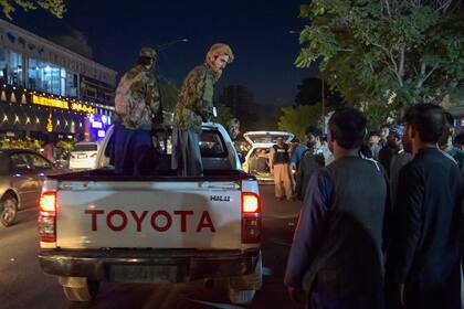 Combatientes talibanes se trasladan en una camioneta mientras los voluntarios traen a los heridos para recibir tratamiento después de poderosas explosiones, que mataron al menos a una decena de personas, fuera del aeropuerto de Kabul