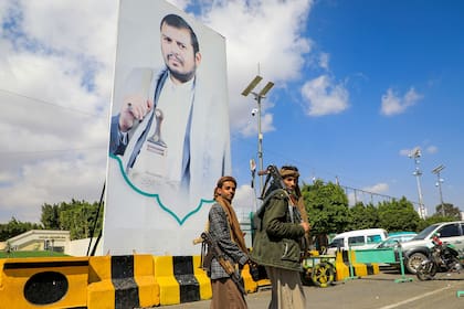 Combatientes yemeníes pasan junto a un gran retrato del líder hutí Abdulmalik al-Huthi en una calle de Saná el 18 de enero de 2024. (MOHAMMED HUWAIS / AFP)�