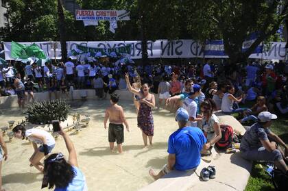 En un día de altas temperaturas, la gente se refresca en la fuente de Plaza de Mayo