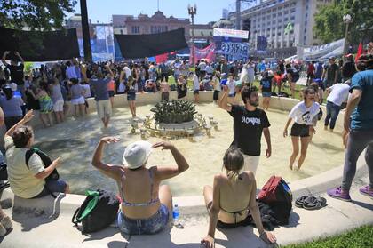 En un día de altas temperaturas, la gente se refresca en la fuente de Plaza de Mayo