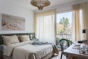 Como foco más oscuro, el respaldo parece envolver la cama vestida en un mismo tono. Lámpara colgante de ratán.