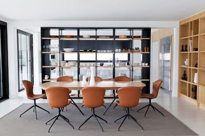 La biblioteca abierta de hierro y madera es un diseño de las arquitectas, al igual que la mesa rodeada con sillas de cuero con patas de hierro (Bo Concept).