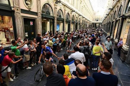 Competidores saludan al público al pasar por la Galería Real San Huberto, uno de los sitios icónicos de la capital belga.