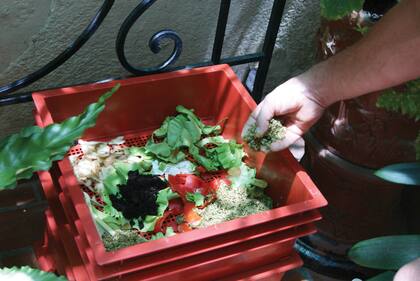 Compostera en un balcón urbano con restos vegetales
