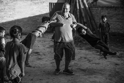 El sacerdote Juani Rosasco juega con chicos en el patio del centro barrial