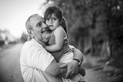 El sacerdote Juani Rosasco con una nena del Barrio Obrero; él llegó a Ingeniero Juárez hace cuatro años