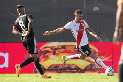 Con cuidado para evitar que la pelota dé en uno de sus brazos, Milton Céliz va a bloquear un disparo de Leandro González Pirez; el defensor de River estuvo en bajo nivel y fue amonestado y sustituido para evitar que resultara expulsado.