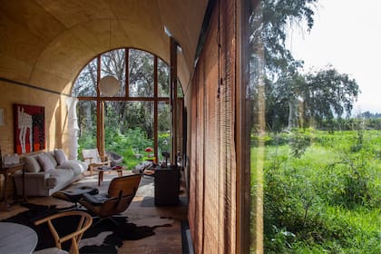 Con grandes ventanales de suelo a techo, el paisaje se convierte en una extensión de la casa, proporcionando una vista panorámica y el ingreso de luz natural. Sofá diseñado por el decorador chileno Mario Matta.