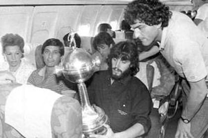 Sergio Batista lleva la Copa Libertadores en sus manos; a su derecha, el Piojo Yudica, una leyenda del fútbol argentino