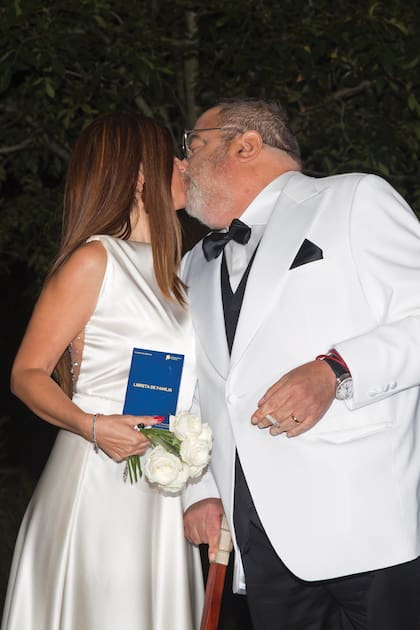 Con la libreta de familia, el bouquet de rosas y él, cigarrillo en mano, los recién casados se besan para las cámaras tras la ceremonia religiosa. 