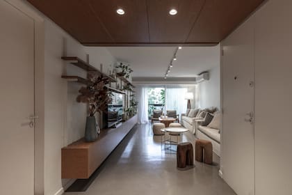 Con la premisa de ganar claridad sin perder calidez, la madera natural de petiribí se aplicó en la isla, en cielo raso junto a la puerta de entrada y en el mueble que recorre el living