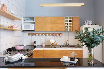 Con la tapa de la mesada negra y delgada y los frentes de madera de un tono similar al de la mesa de comedor y la escalera, la cocina rejuveneció sin demasiadas complicaciones.