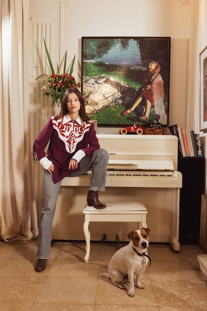 Con Lebron, el Jack Russell Terrier de los Agulla, con botas texanas y un outfit de Jazmín Chebar. Arriba del piano, un cuadro de Mondongo.