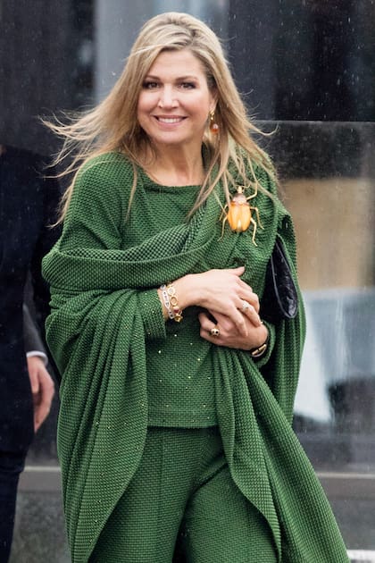 Con look total verde, Máxima usa un gancho con forma de escarabajo gigante para sostener su capa.