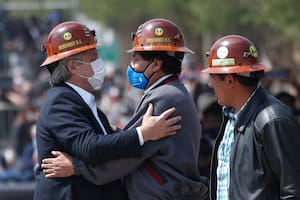 Con los cascos de trabajo de los mineros bolivianos, el expresidente de Bolivia, Evo Morales, en el centro, y el presidente de Argentina, Alberto Fernández, a la izquierda, se abrazan en medio del puente fronterizo que conecta la ciudad argentina de La Quiaca con la ciudad boliviana de Villazón, el