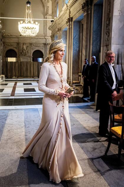 Con mangas largas, cuello cruzado y pedrería, el vestido que lució Máxima en la noche del lunes es un diseño creado por el holandés Jan Taminiau.