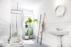 Con piso de cemento alisado y revestimiento de azulejos blancos, el baño tiene un lavatorio de pie que los chicos rescataron de una obra cuya iluminación realizaron.