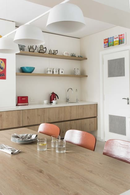 Con reforma e interiorismo de la arquitecta Patricia Daiez, esta cocina tiene un barral con tres pantallas de Via Luce sobre la mesa acompañada por sillas de El Yeite.