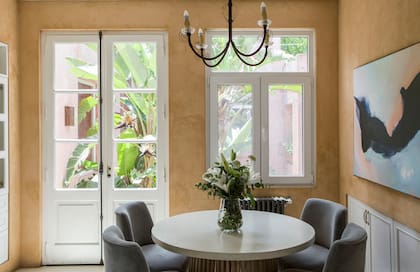 Con salida al patio central, el comedor diario tiene mesa de microcemento y sillas tapizadas en pana. El cuadro es obra de la dueña de casa, Verónica del Olmo (Il Vero Art).