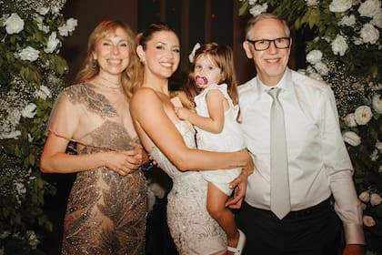 Con su hija en brazos, la modelo
posa junto a sus padres, Marina Solomonovici y Roberto Demner.