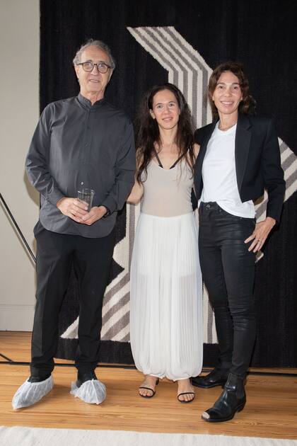 Con sus pies enfundados entre obras originales, el arquitecto Edgardo Minond junto a Flor y María Cherñajovksy. El proyecto Lalana realza el trabajo artesanal y destaca a artistas argentinos