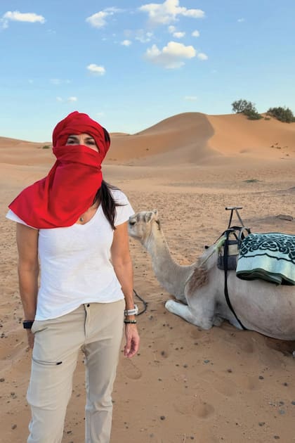 Con turbante, remera blanca y pantalón estilo cargo, posa en el desierto junto a un camello