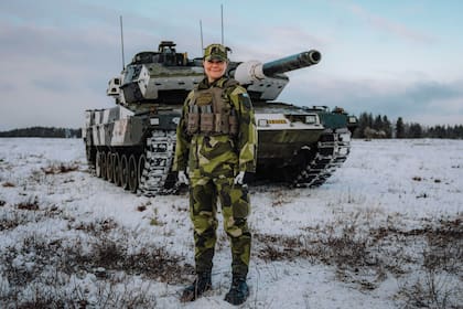 Con uniforme de faena, posa frente a un tanque