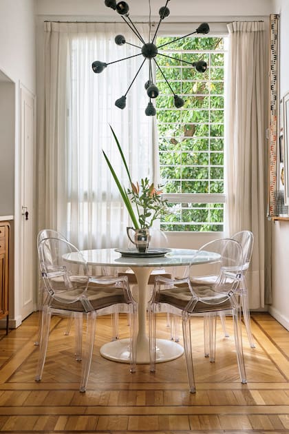 Conectado con el living y con vista al patio arbolado, el comedor con mesa ‘Tulip’, sillas ‘Louis Ghost’ de Philippe Starck y lámpara estilo Sputnik es el lugar preferido de Mario para almorzar.