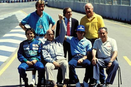Ayrton Senna levanta el brazo de Juan Manuel Fangio, en un encuentro de campeones de F1 en Australia 1990. Completan James Hunt, Jackie Stewart y Denis Hullme, arriba, más Nelson Piquet y Jack Brabham