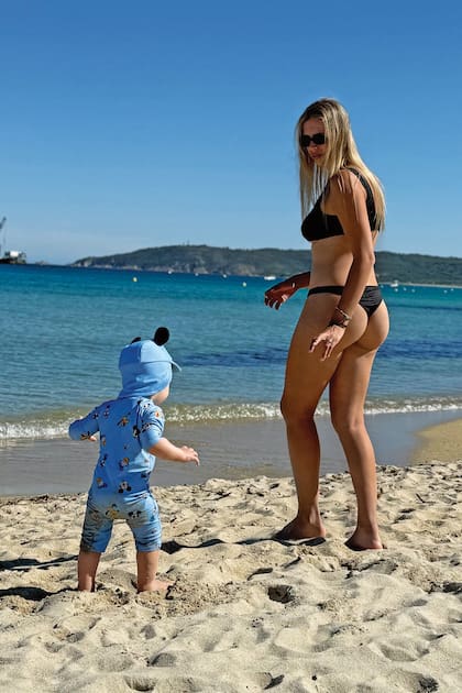 Coni juega con su hijo, vestido
con enterito de protección solar con
estampa de Mickey Mouse y gorro.