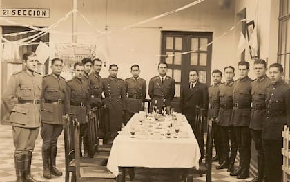 Conscripto del Ejército Argentino John Stower (segundo, comenzando desde la derecha) junto a sus compañeros de promoción clase 1916 al concluir el Servicio Militar en el Regimiento de Infantería de Montaña N°20 “Cazadores de los Andes” con asiento en Jujuy. Se aprecia un cuadro del Cabildo además de algunas banderas Argentinas. (Cortesía de Patrick Wilson).