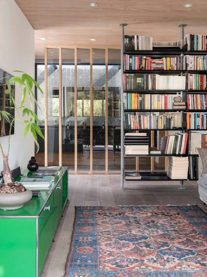 Consola verde ‘Haller’ (USM). Biblioteca diseñada por Dieter Rams (Vitsœ), un clásico. Por detrás del antebaño, patio interno revestido en venecitas negras.