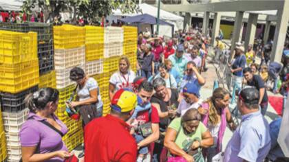 Consumidores venezolanos hacen fila en un mercado de Caracas para comprar alimentos subsidiados